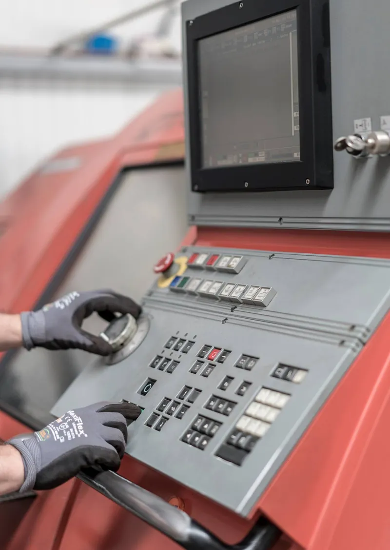 Hände an der Steuerung einer CNC-Drehmaschine
